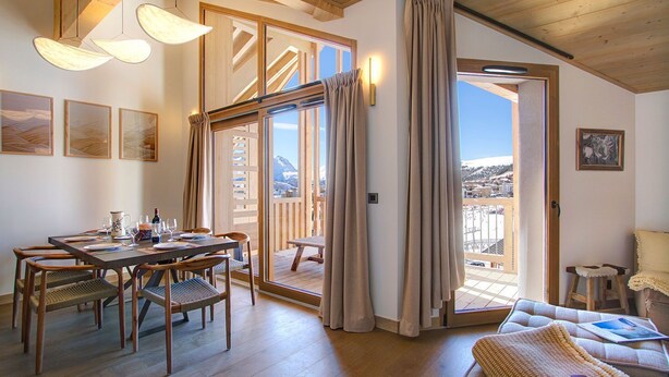 Ein gemütliches Zimmer mit Essbereich, einer Couch und einem Balkon mit Bergblick.