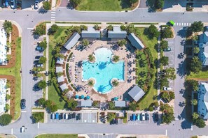 Vue aérienne d’un complexe hôtelier doté d’une piscine centrale, de plusieurs espaces de détente et d’un parking.