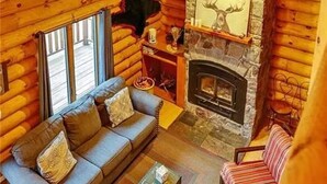 A log cabin interior with a stone fireplace, a sofa, and a dining table. - Spacious 3 Story Cabin. Access to UTV/ATV Trails & Near Lake Arbutus (Merrillan)