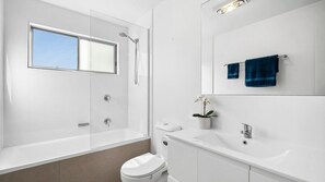A modern bathroom with a glass-enclosed shower, a toilet, a sink, and a mirror. - 2/8 Pandanus, Beautiful townhouse walking distance to beach (Mudjimba)