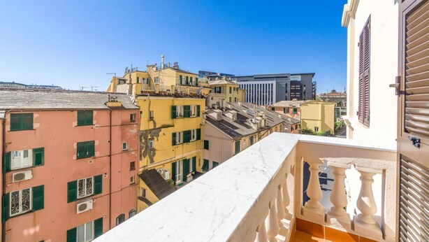 A balcony with a marble ledge overlooking a cityscape with buildings of various architectural styles.