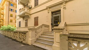 A building with a staircase leading to a door, a balcony, and a fence with decorative elements.