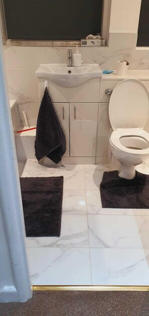A bathroom with a toilet, sink, and a towel hanging on the wall. - Marahome (Watford)