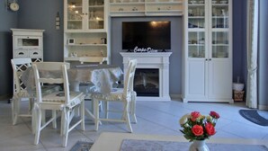 A living room with a TV, white furniture, and a fireplace.