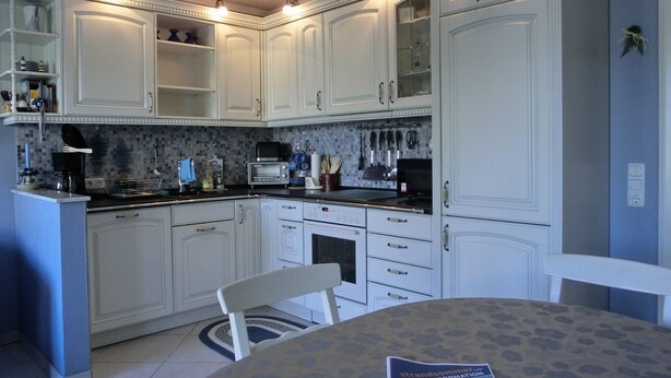 A kitchen with white cabinets, a dining table, and a chair.