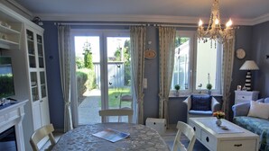 A dining area with a table and chairs, a kitchen area with cabinets, a sofa, and a chandelier.