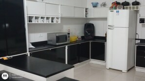 A kitchen with white cabinets, a microwave, a refrigerator, and various kitchen appliances. - Paraíso da Natureza (Ibiúna)
