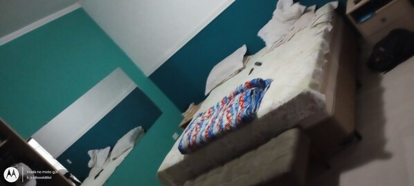 A room with a bed, a pillow, a blanket, and a suitcase.