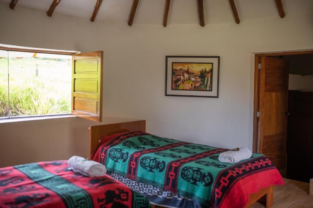 A room with a bed, a painting, and a window with a view of greenery.