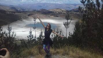 A person standing on a rocky terrain with a view of a lake and mountains in the background.