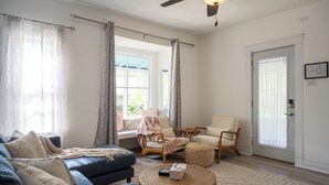 A living room with a blue sofa, a round wooden coffee table, and two chairs. - Corner Cottage, Downtown Saugatuck  (Saugatuck)