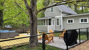 A house with a covered patio, outdoor seating, and a large tree in the foreground. - Corner Cottage, Downtown Saugatuck  (Saugatuck)