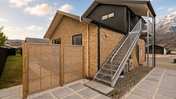 A modern building with a stone facade, a metal staircase, and a wooden fence.
