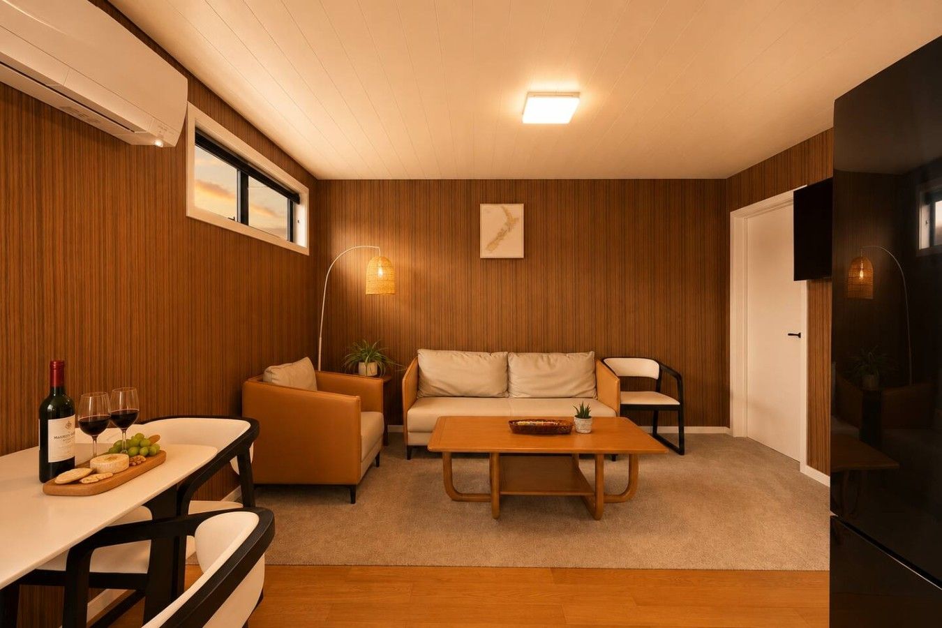 A modern living room with a sofa, armchairs, a coffee table, and a dining area with a table and chairs.