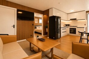 A compact living space with a kitchenette, a dining area, and a bedroom.