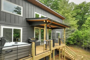 Een modern huis met terras, jacuzzi en buitenbarbecue.