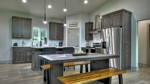 Una cocina moderna con armarios de madera oscura, un refrigerador de acero inoxidable y una isla central con asientos.