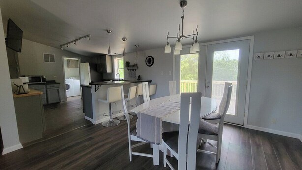 A modern kitchen with white cabinetry and a dining area with a white table and chairs.