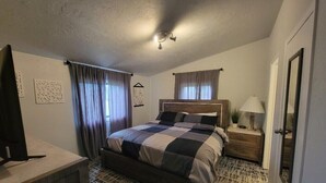 A bedroom with a bed, a bedside table with a lamp, a dresser, and a mirror.