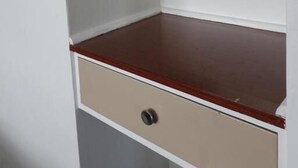 Un angolo di una stanza con un bancone in legno, un cassetto beige e una parete bianca.