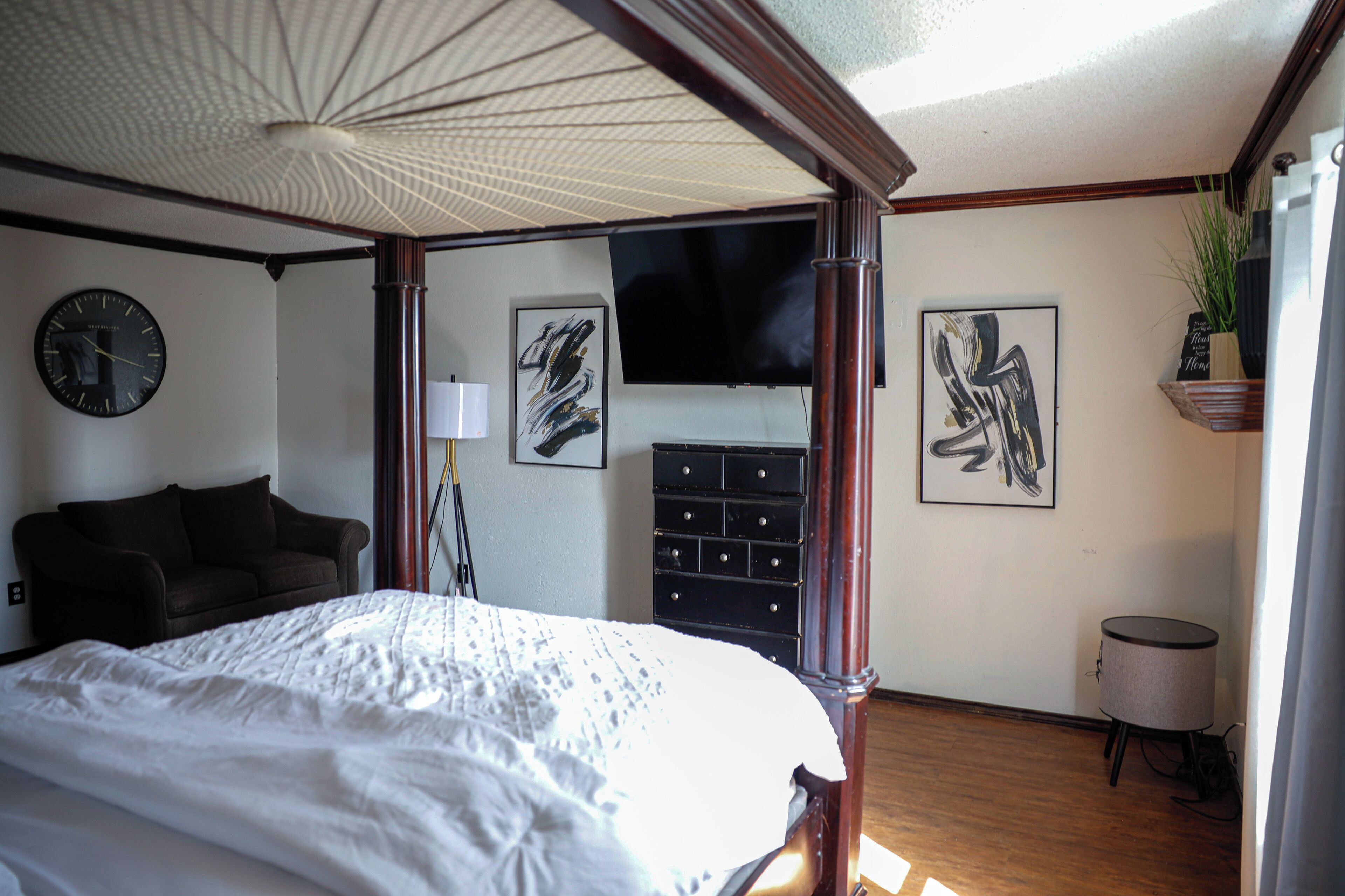 Un dormitorio con una cama grande, un aparador, un televisor y obras de arte en las paredes.