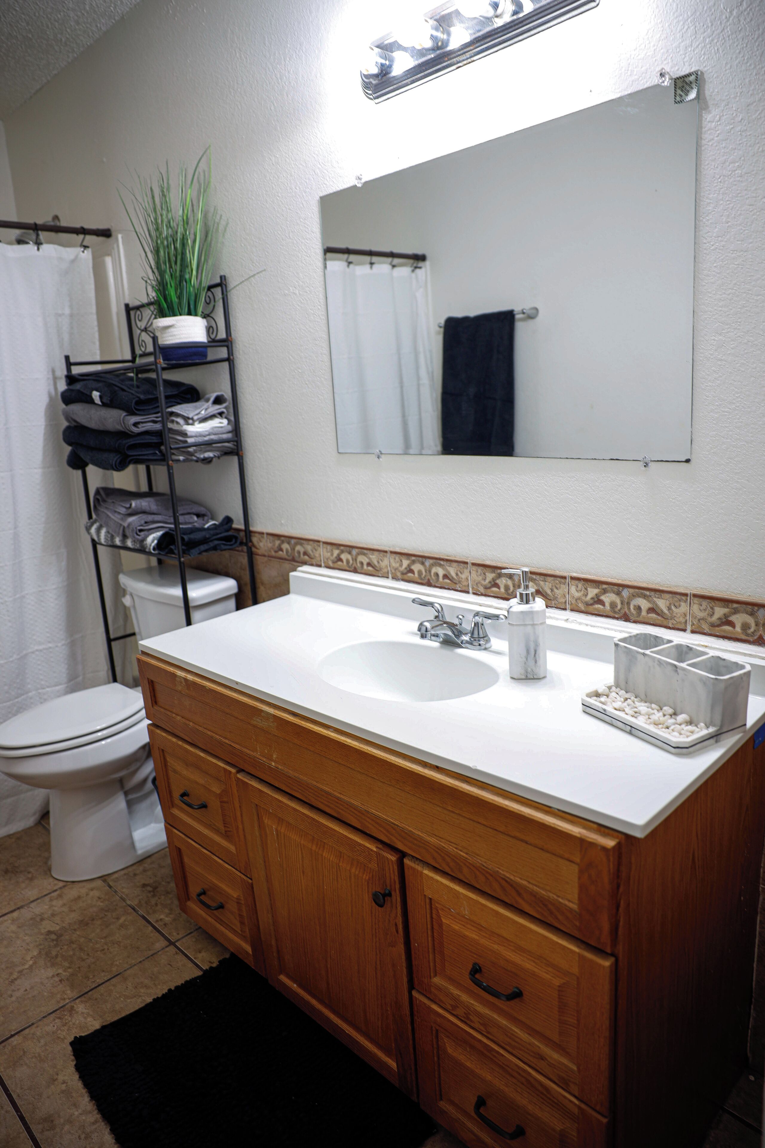 A bathroom with a white sink, wooden vanity, and a mirror above the sink.