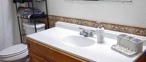 A bathroom with a white sink, wooden vanity, and a mirror above the sink.