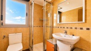 A bathroom with a toilet, shower, sink, and a window. - Apartamento el Arcin (Llanes)