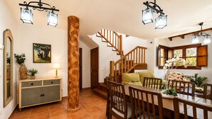 Ein Essbereich mit Holztisch und -stühlen, einer Treppe und einer großen Holzsäule.