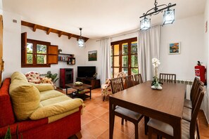 A living room with a sofa, TV, dining table, chairs, and a fireplace.