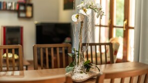 Ein Esstisch mit einer Vase weißer Orchideen.