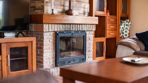 Una sala de estar con chimenea, armarios de madera y televisor.
