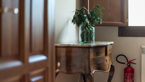 Un meuble en bois surmonté d’un vase en verre contenant des plantes vertes, le tout posé sur un comptoir en marbre.