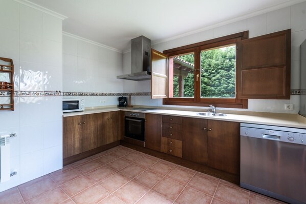 Una cocina con armarios de madera, microondas integrado, estufa y lavavajillas.