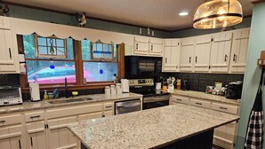 A kitchen with granite countertops, white cabinetry, and a large island. - The Nest is Best in Bear Paw, Murphy, NC.  (Murphy)