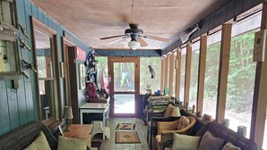 A covered porch with wooden flooring, wicker furniture, and a ceiling fan. - The Nest is Best in Bear Paw, Murphy, NC.  (Murphy)