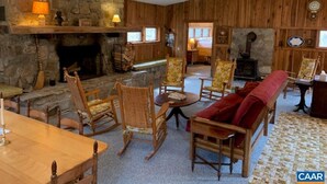 Une pièce chaleureuse avec une cheminée en pierre, des meubles en bois et un ventilateur de plafond.