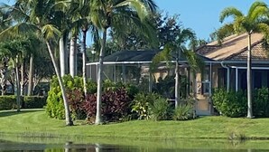 Ein Haus mit Swimmingpool, umgeben von Palmen und einem gepflegten Rasen.