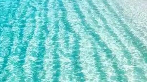 Ein Blick auf einen Strand mit türkisblauem Wasser und weißem Sand.