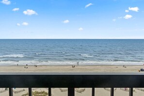 Vista de la playa con cielo despejado, mar tranquilo y algunas personas en la arena.