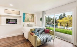 Et moderne soveværelse med seng, sofa, et kort på væggen og udsigt til en park gennem store vinduer.