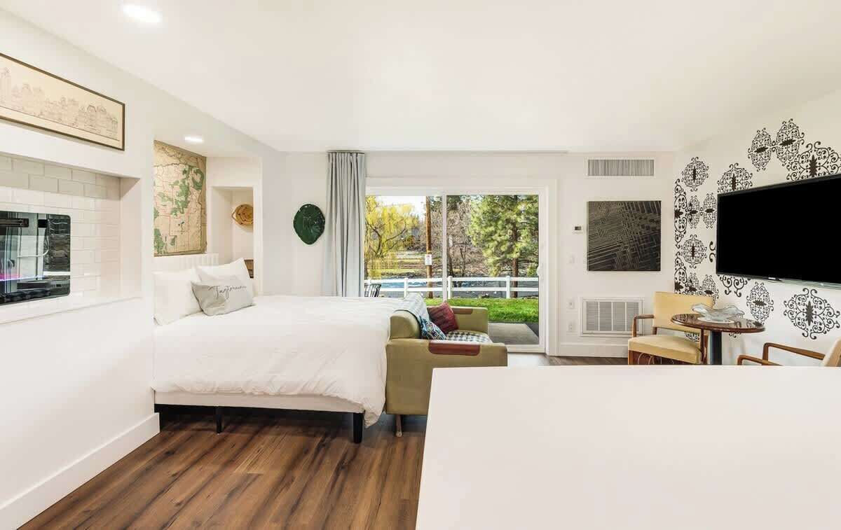 A bedroom with a bed, a sofa, a TV, and a window with a view.
