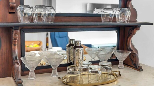 Un miroir, une table sur laquelle sont disposés des verres et une bouteille.