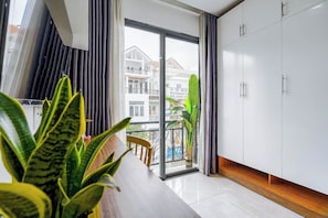 A modern apartment with a balcony, large windows, and a dining area with a table and chairs.