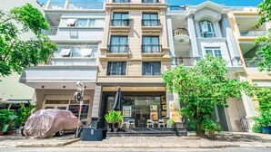 Un hôtel à plusieurs étages doté d’une entrée principale, d’un espace extérieur aménagé pour s’asseoir et de plantes en pot.
