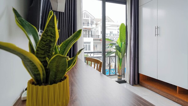 Un intérieur moderne avec un plancher en bois, un mur blanc et une fenêtre donnant sur un immeuble et un balcon.