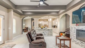 A spacious living area with a leather recliner, a fireplace, and a kitchen in the background.