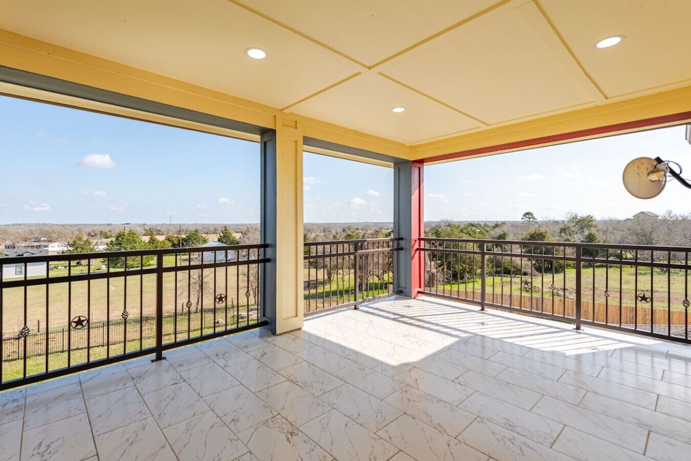 Ein geräumiger Balkon mit freiem Blick auf die umliegende Landschaft, mit Fliesenboden und Metallgeländer.
