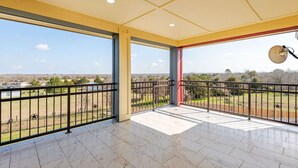 A spacious balcony with a clear view of the surrounding landscape, featuring a tiled floor and a metal railing.