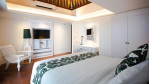 A bedroom with a bed, a chair, a vanity, and a wardrobe. - CALM VILLA SEMINYAK (Seminyak)